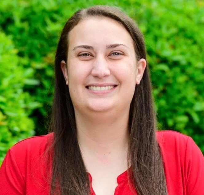 a headshot of carolina neurodiversity center's chief executive officer and founder, Emily Walsh. Emily is a white woman with medium length brown hair and she is wearing a red shirt.
